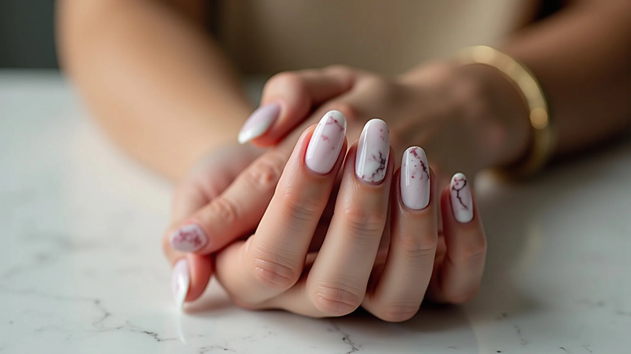 Mãos femininas exibindo unhas de gel com efeito marmorizado.