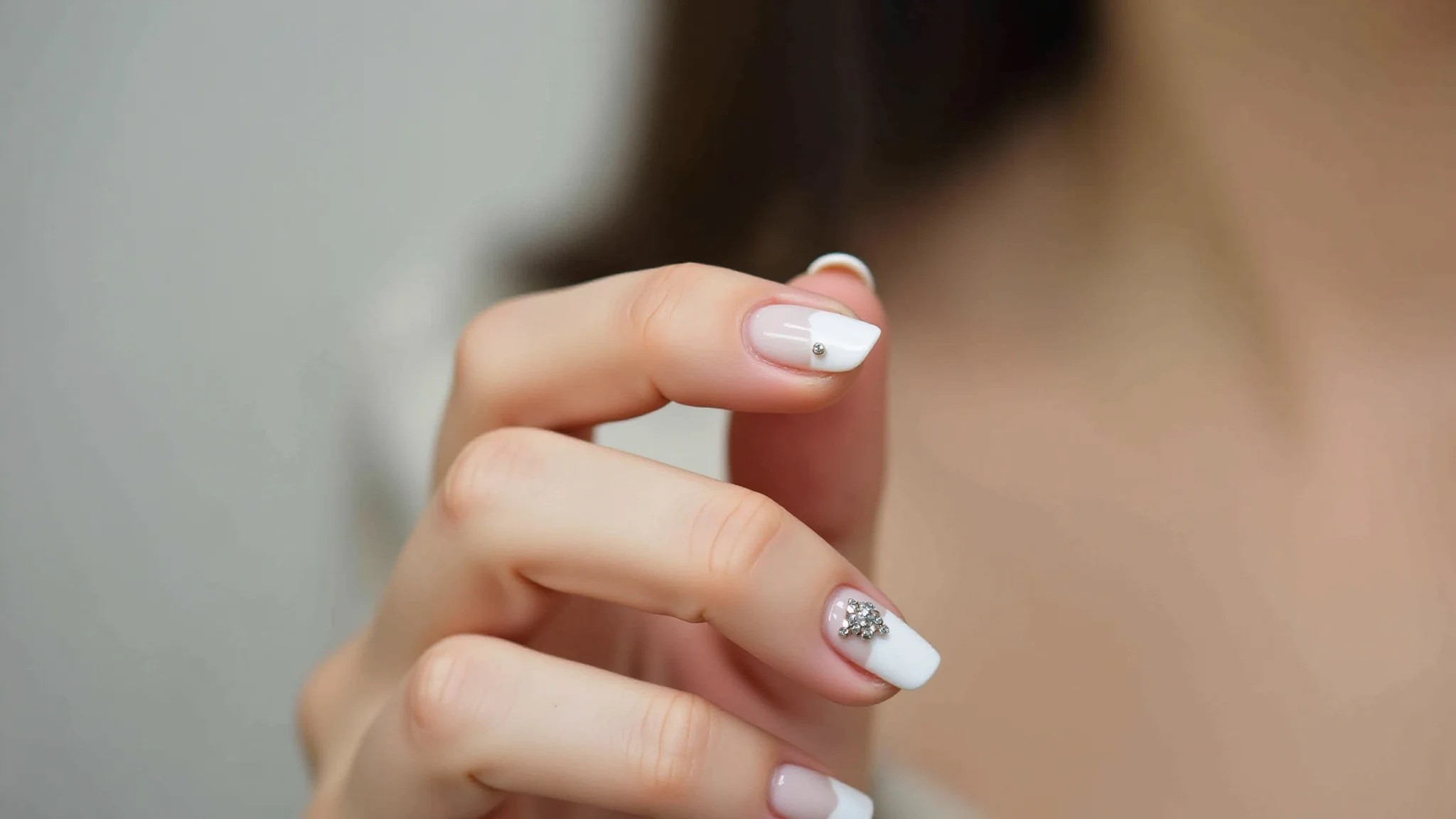 Unhas com pedraria delicada, minimalismo chic, ponto de luz estratégico.