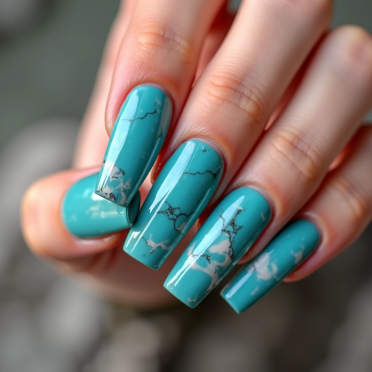 Unhas quadradas azul turquesa com efeito marmorizado.