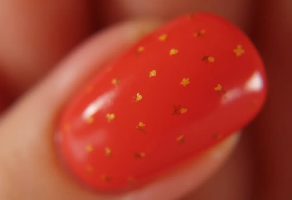 Unhas decoradas com tema de morango segurando um morango fresco.