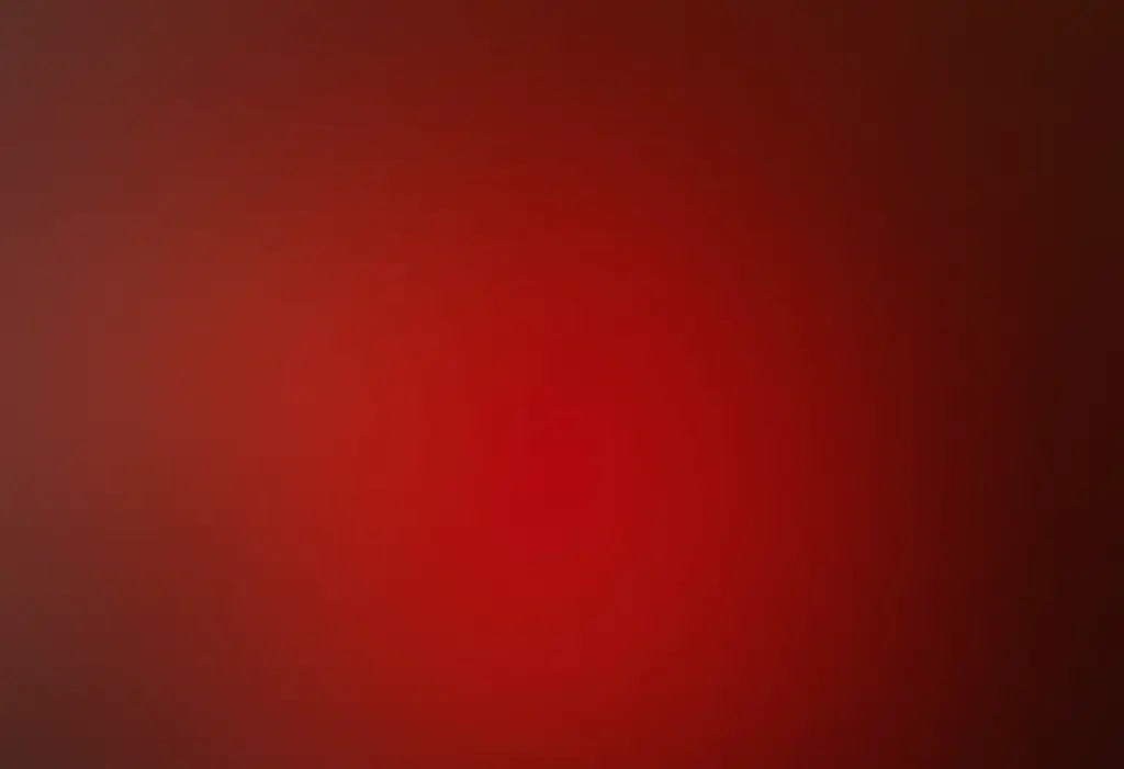 Unhas degradê vermelhas segurando perfume