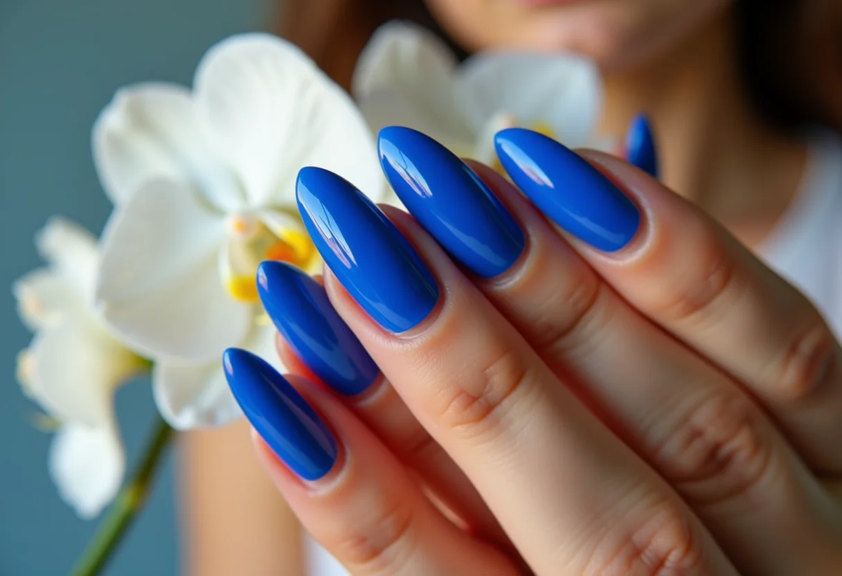 Unhas stiletto azul royal segurando orquídea branca